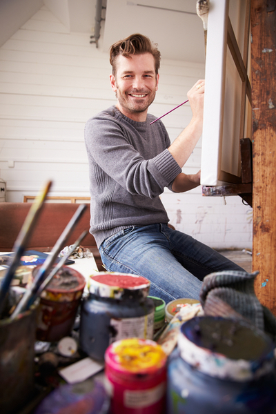 Portrait Of Male Artist Working On Painting In Studio